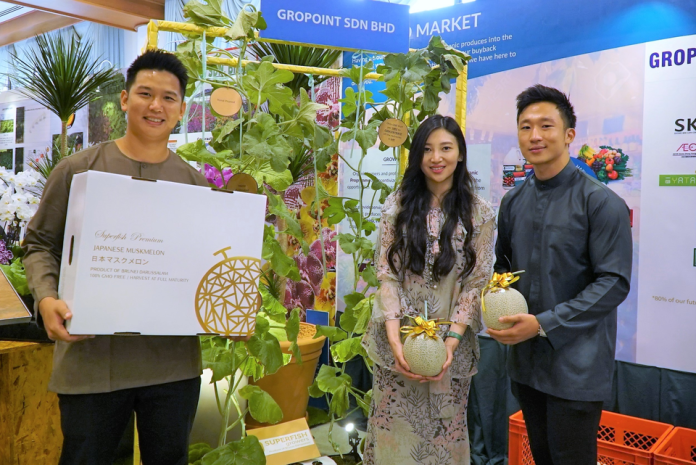 Superfish Growers' Managing Director Eileen Lee Hui Shi (C) and Chief Technical Officer Lee Wei Sheng (R) holding their muskmelons at their booth during YSHHB's Hari Raya celebration last week.